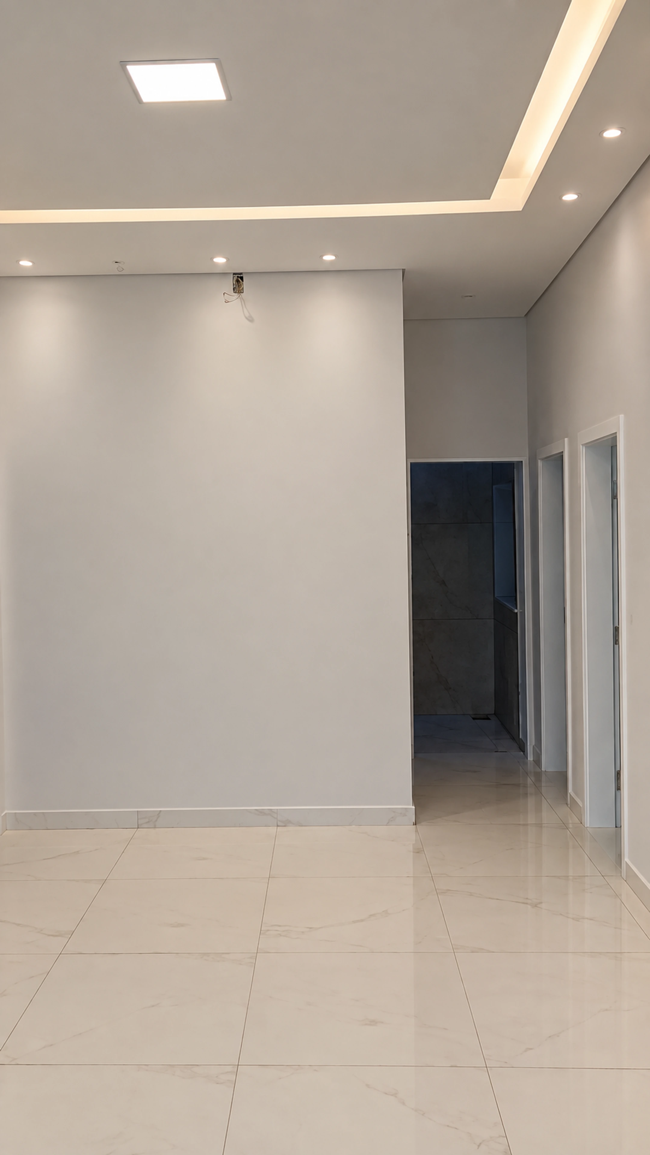 Sala com pintura concluída, iluminação de forro e piso claro em projeto de César em Brasília